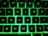 Close-up of hands typing rapidly on a mechanical keyboard with green backlight.