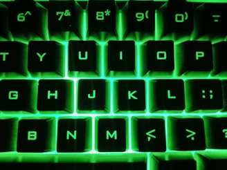 Close-up of hands typing on a sleek keyboard with neon mint green accents in the background.