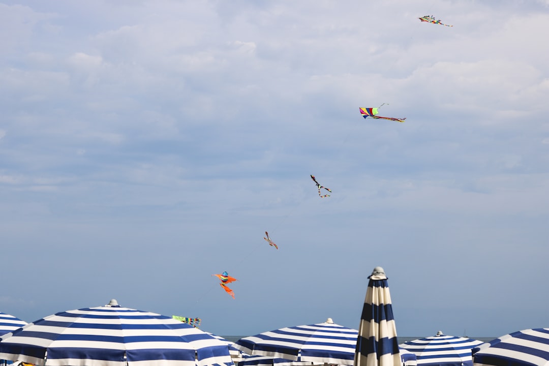 kites in mid air above parasols during day