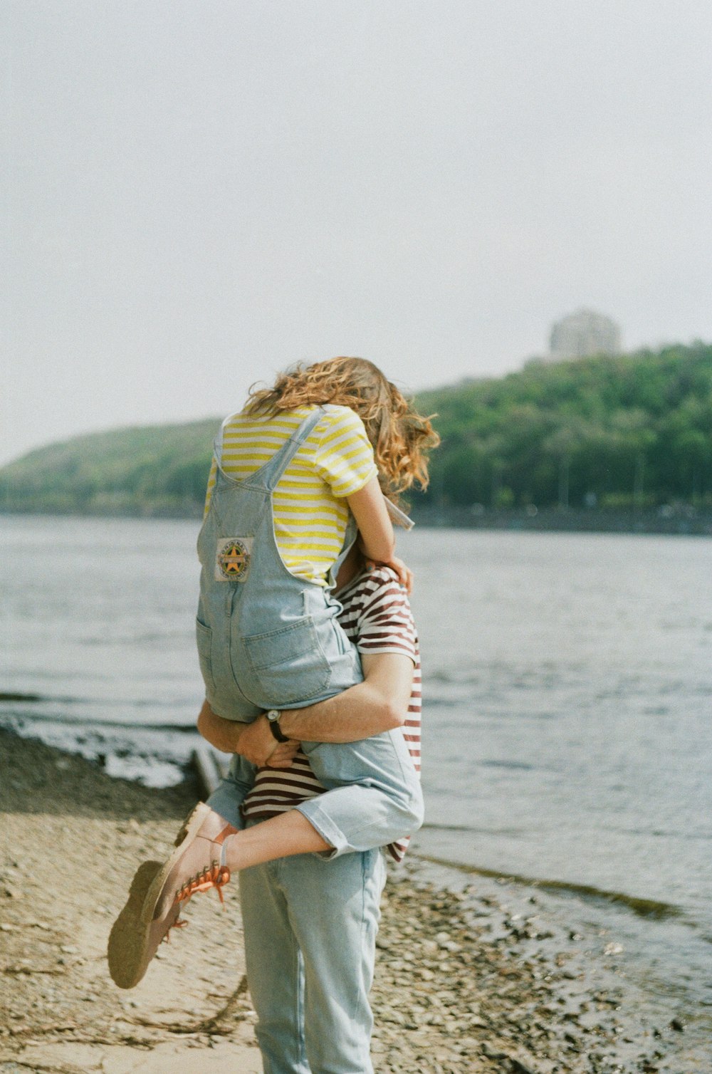 person carrying woman on shore during day