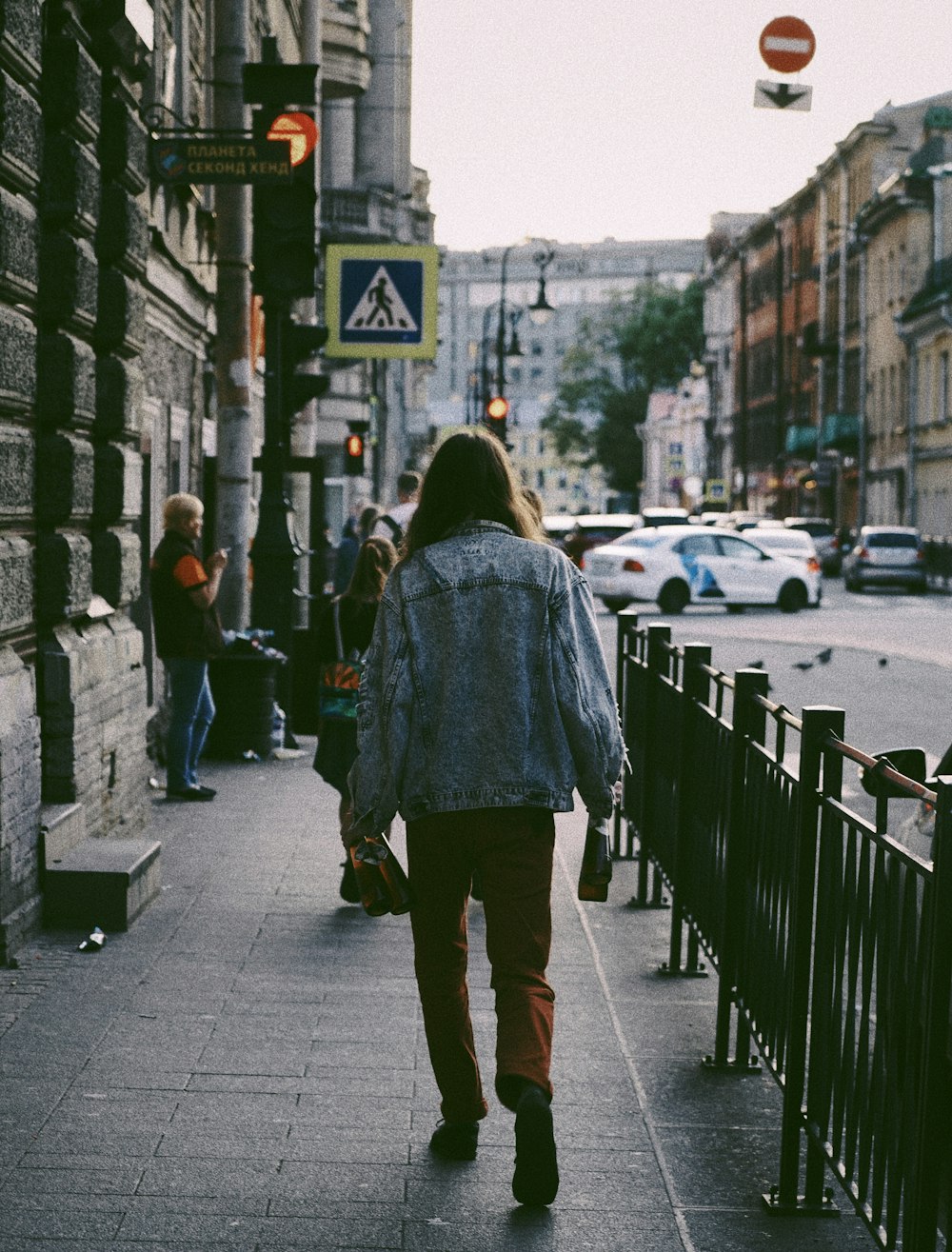 person wearing blue jacket walking on sidewalk