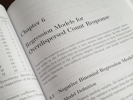 A textbook is open to Chapter 6, titled 'Regression Models for Overdispersed Count Response.' The page discusses various statistical models, including the negative binomial regression model, providing mathematical explanations and theoretical backgrounds.