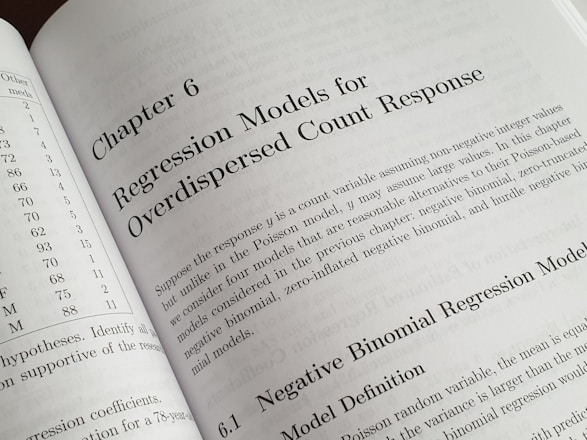 A textbook is open to Chapter 6, titled 'Regression Models for Overdispersed Count Response.' The page discusses various statistical models, including the negative binomial regression model, providing mathematical explanations and theoretical backgrounds.