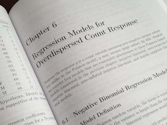A textbook is open to Chapter 6, titled 'Regression Models for Overdispersed Count Response.' The page discusses various statistical models, including the negative binomial regression model, providing mathematical explanations and theoretical backgrounds.