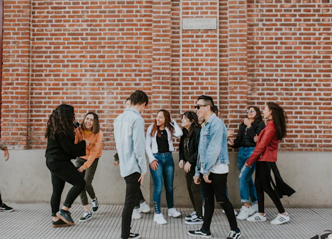 A vibrant group of young people sharing a moment of laughter outside a modern London church building on a sunny day.
