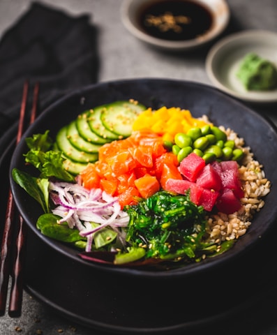 Vibrant poke bowl topped with fresh fish, avocado, and bright tropical fruits in a modern bowl.