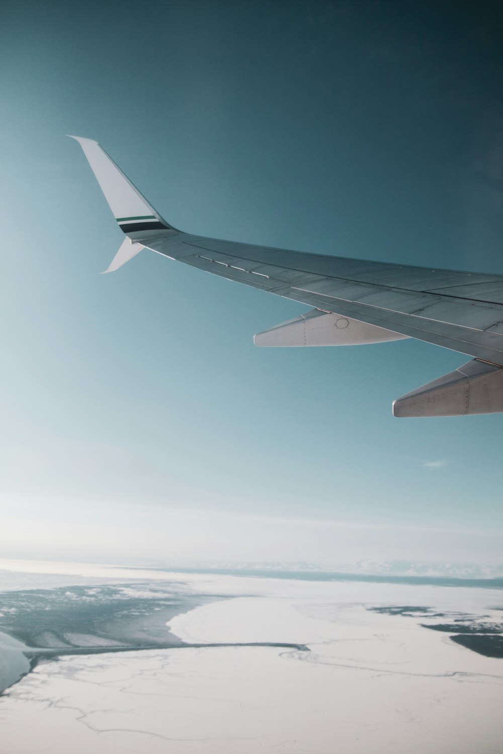 white and gray airplane wing across ice fields