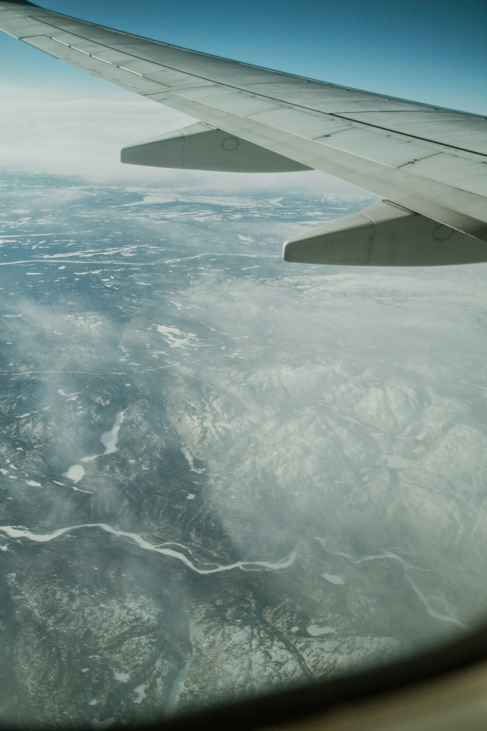 the wing of an airplane flying over a mountain range