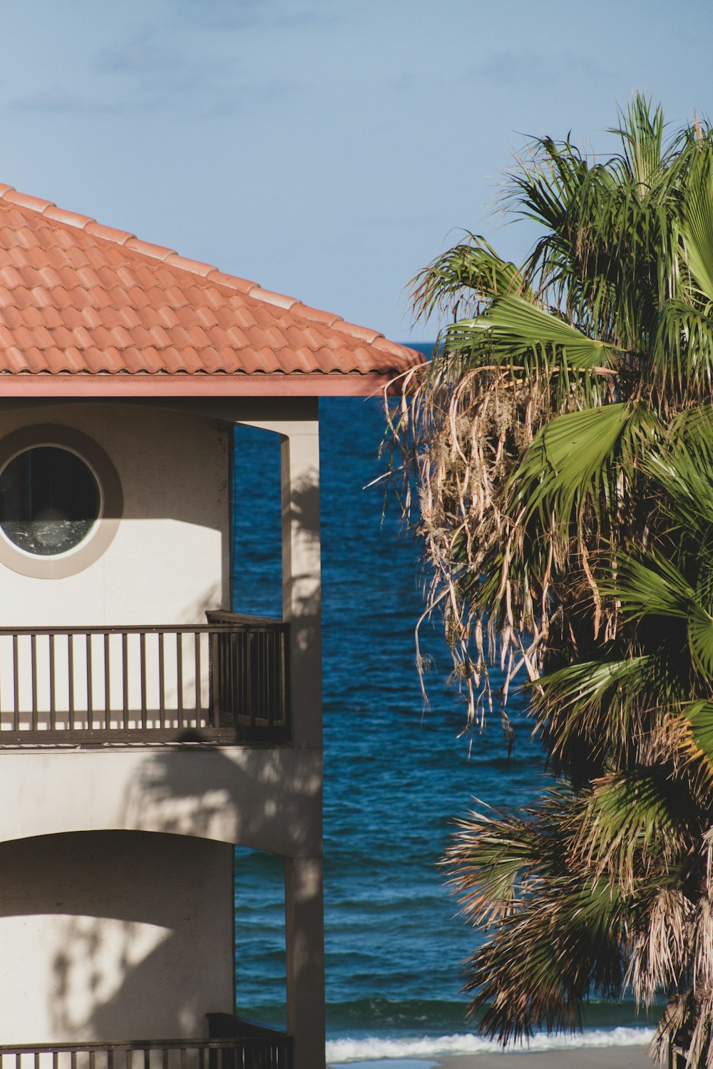 building with balcony and porch beside tree in front of the sea during day