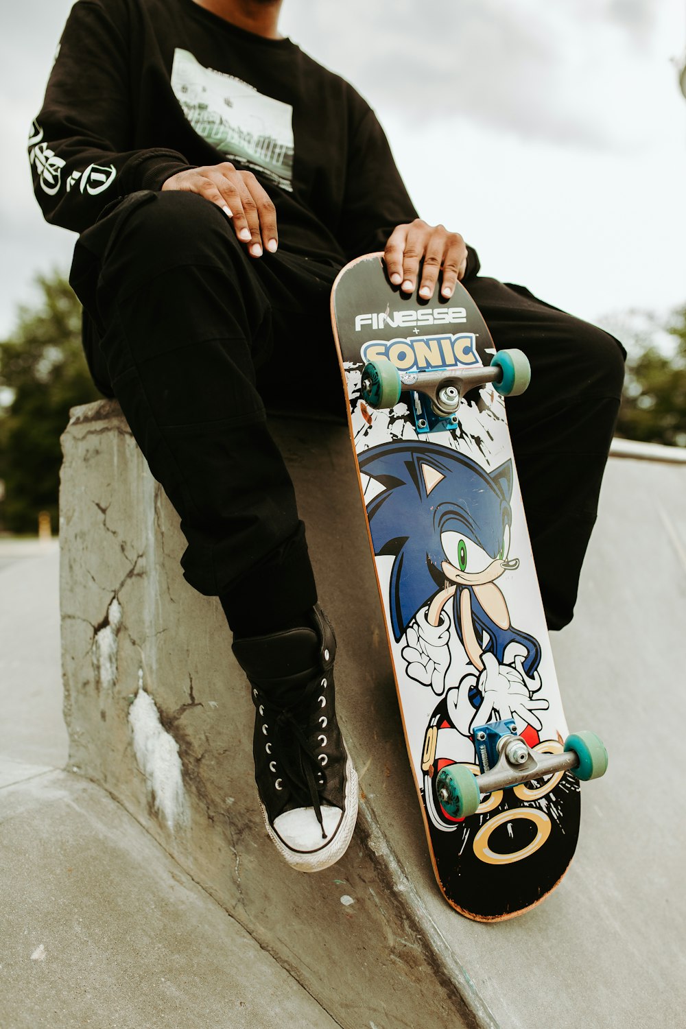 person wearing black long-sleeved shirt holding Finesse Sonic skateboard