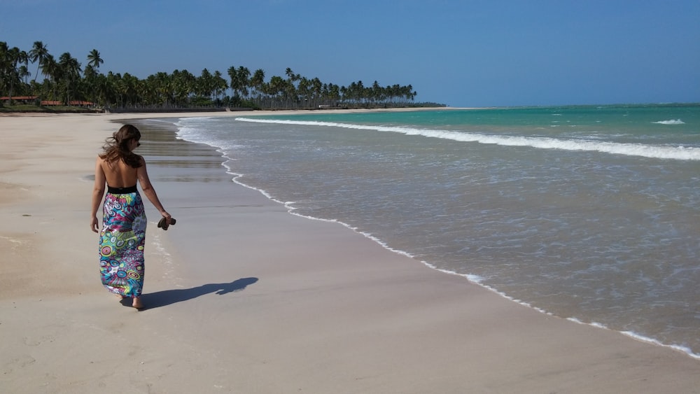 Mujer con vestido caminando por la orilla del mar