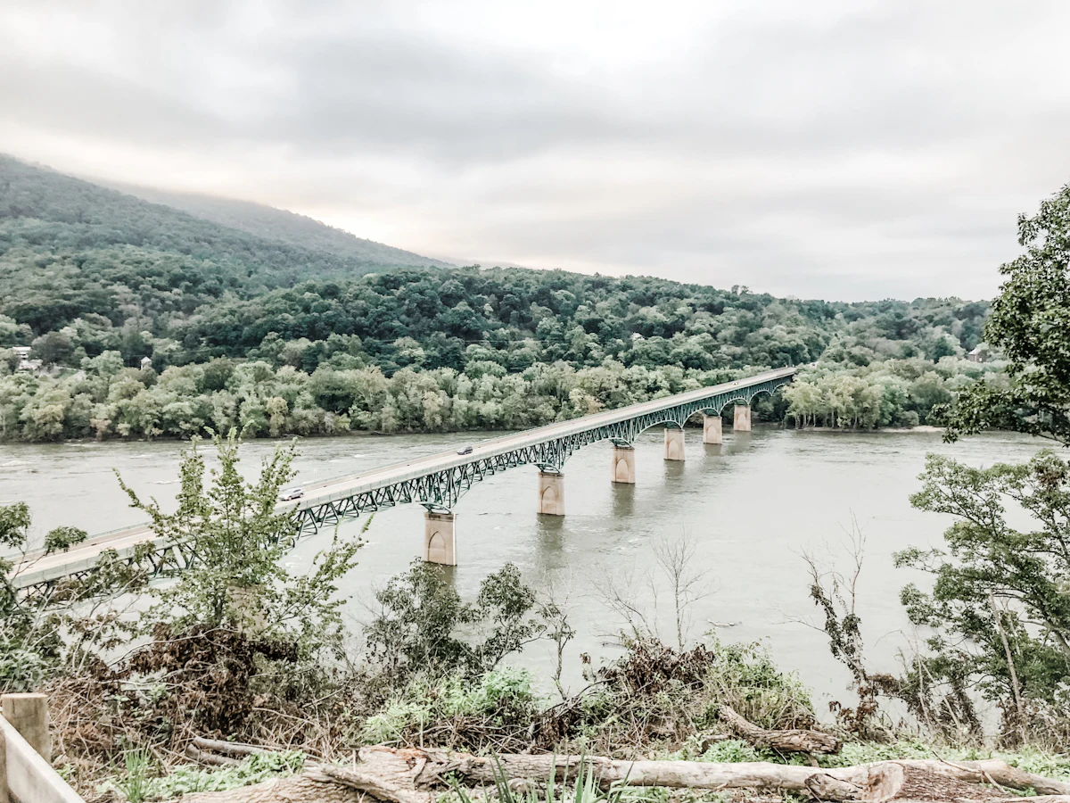 A long road bridge across a wide river at Harpers Ferry, under a wooded ridge