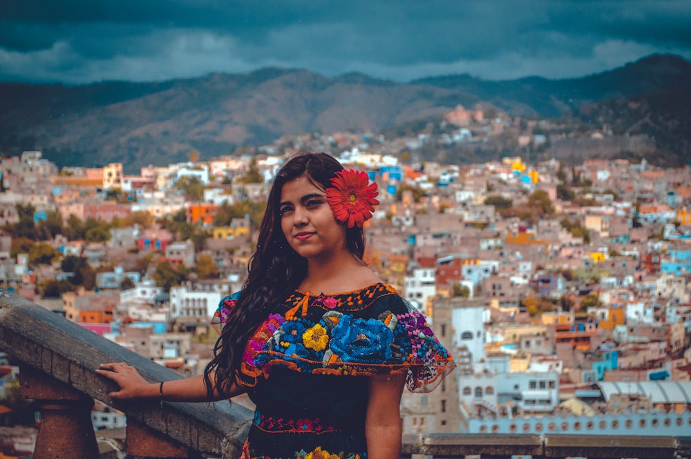 woman with red floral headdress taking photo with city background