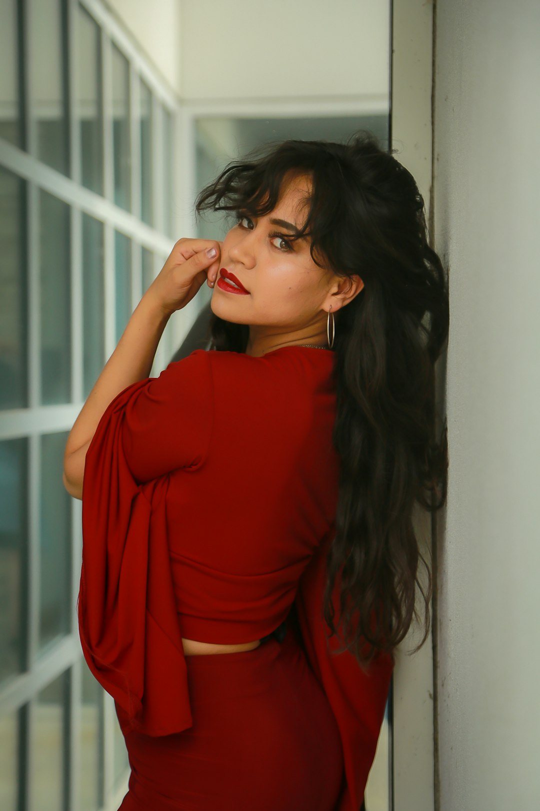 woman wearing red dress standing beside white wall