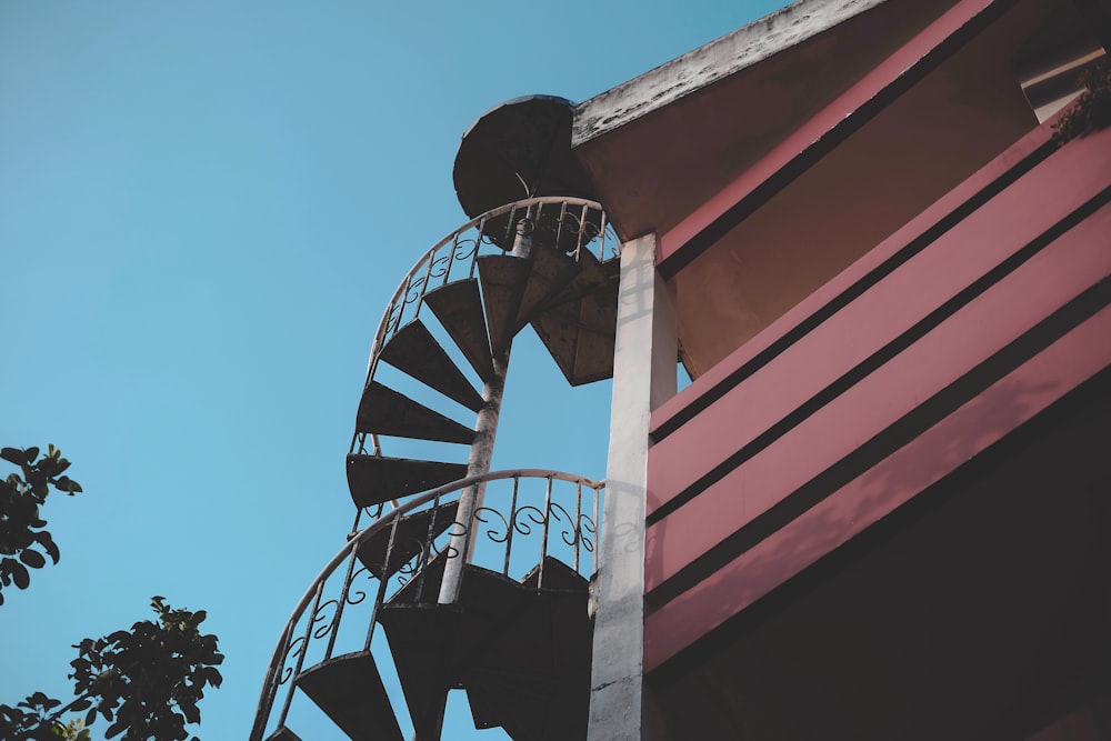 a tall metal spiral staircase next to a red building