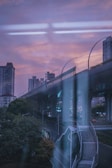 A sweeping view of a sleek metro viaduct cutting through an urban landscape at dusk