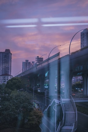 A sweeping view of a sleek metro viaduct cutting through an urban landscape at dusk