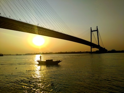 A large concrete bridge spanning a wide river during sunset.
