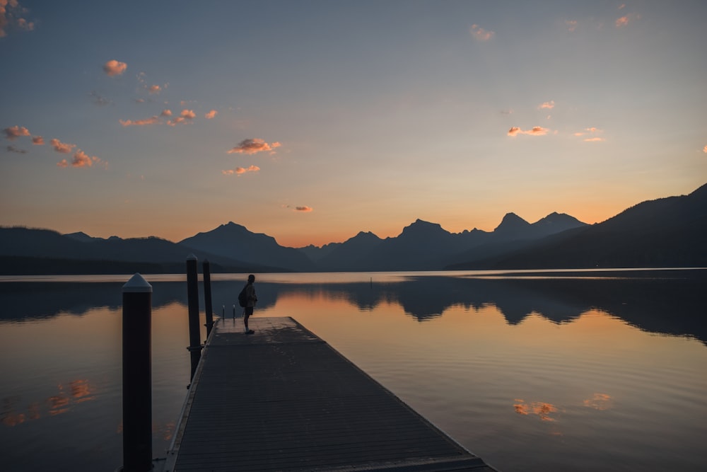 a person standing on a dock at sunset