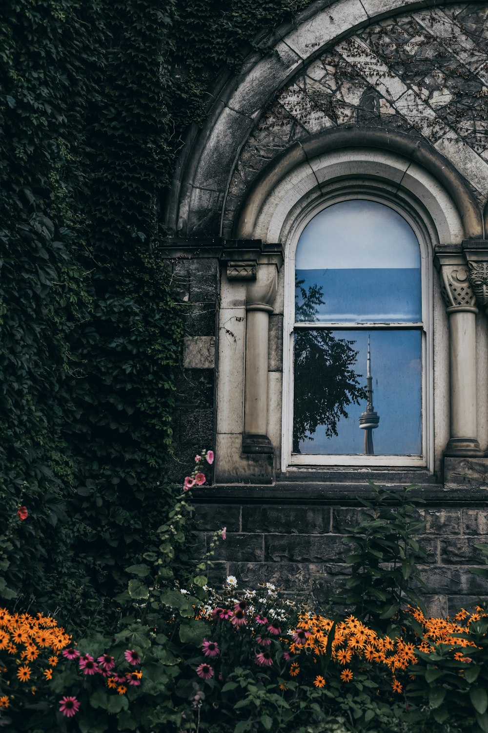 a window in a stone building with flowers around it