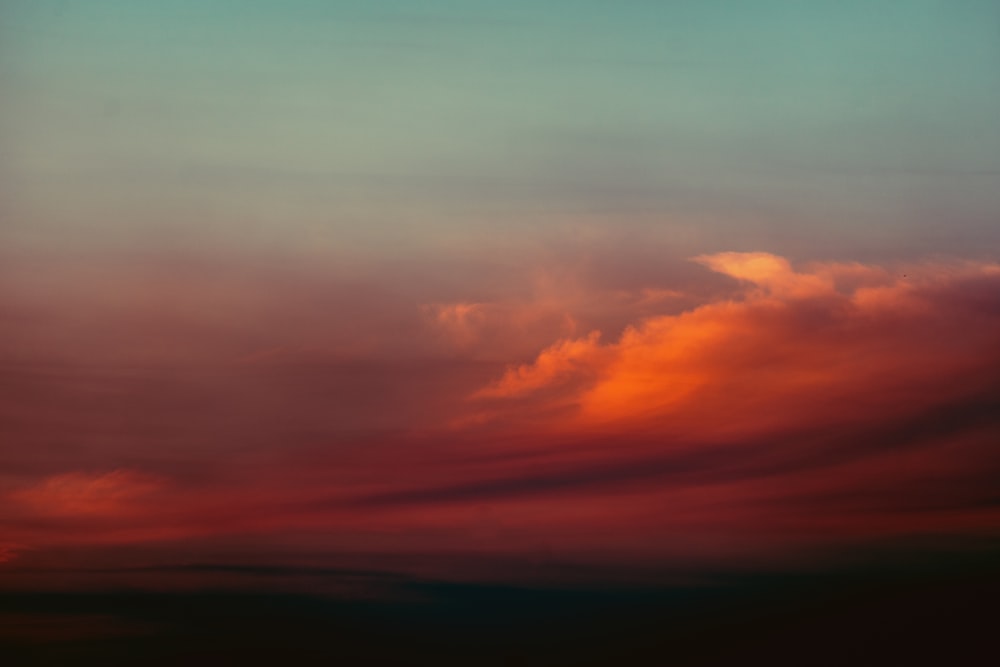 a plane flying in the sky at sunset