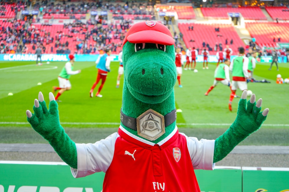 mascotte d’animal vert debout près du champ