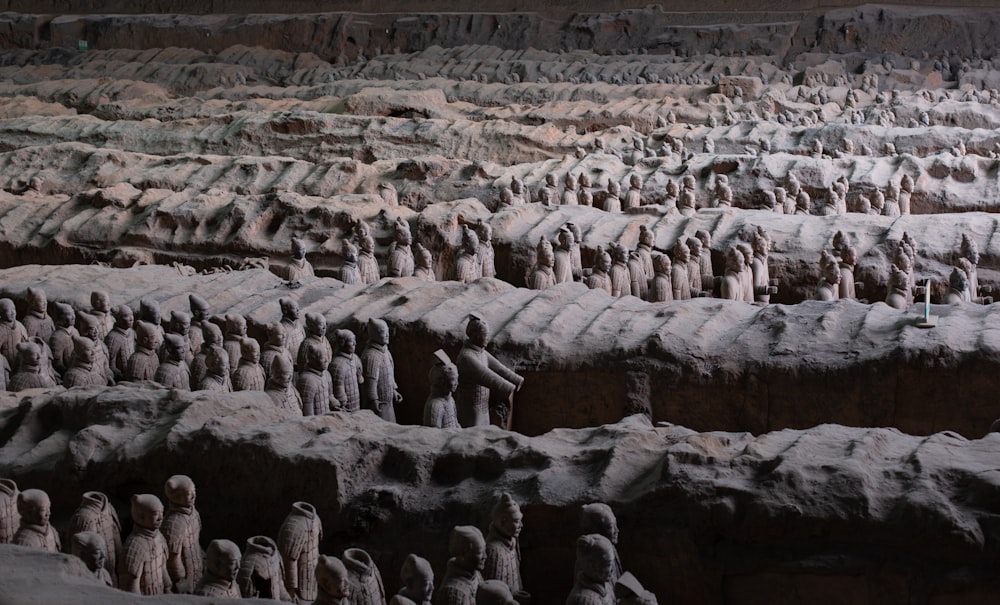 a large group of statues sitting on top of a stone wall