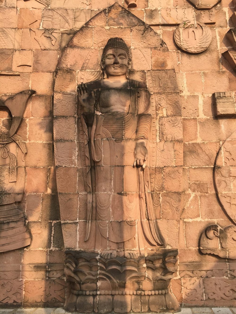 a statue of a buddha in front of a brick wall