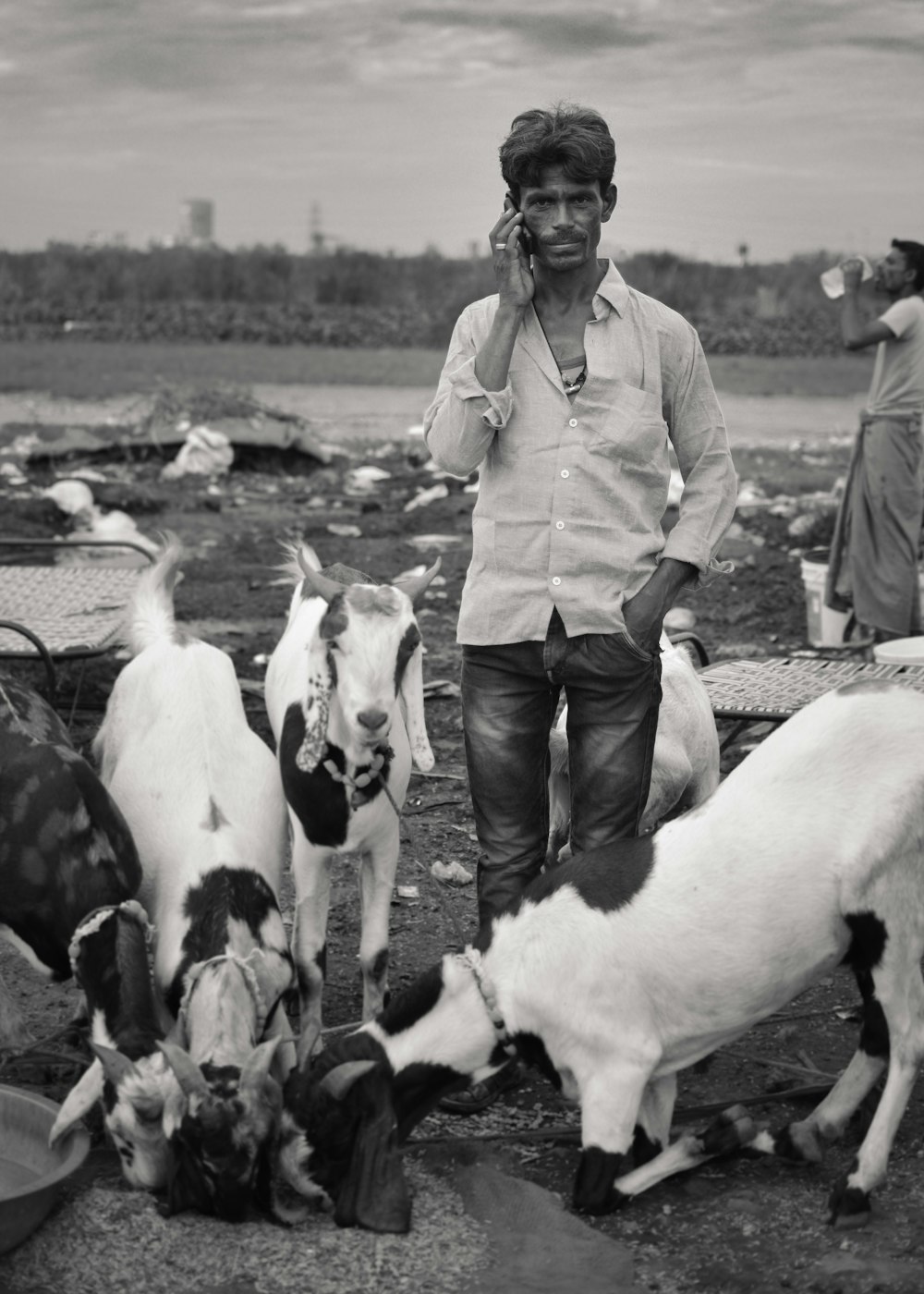 Photo en niveaux de gris d’un homme entouré d’une chèvre