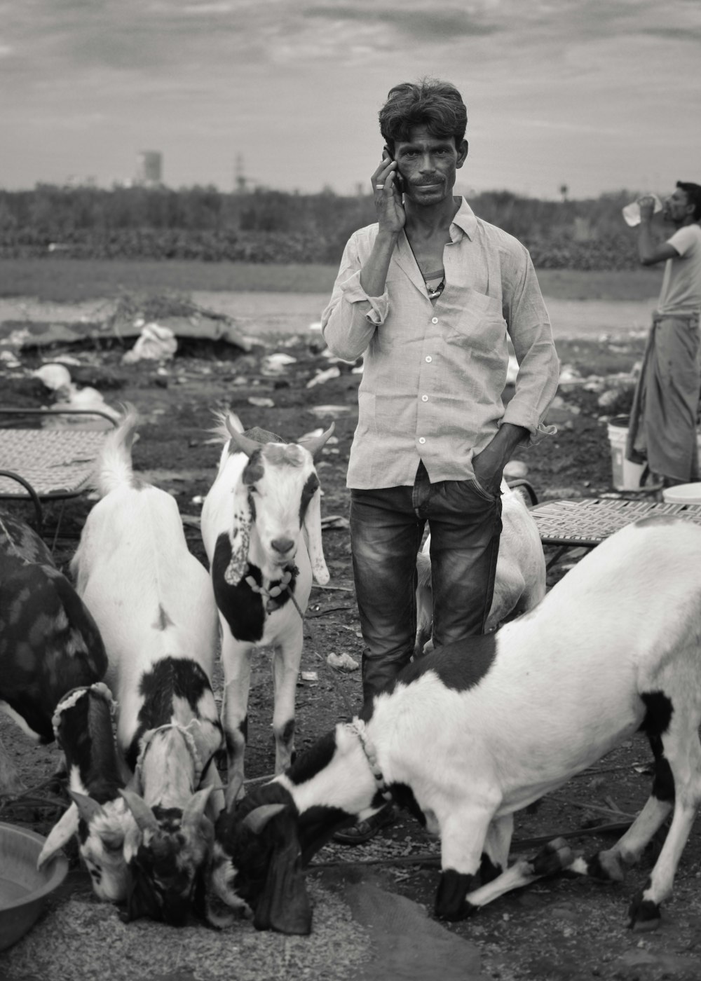 Foto en escala de grises de un hombre rodeado de una cabra