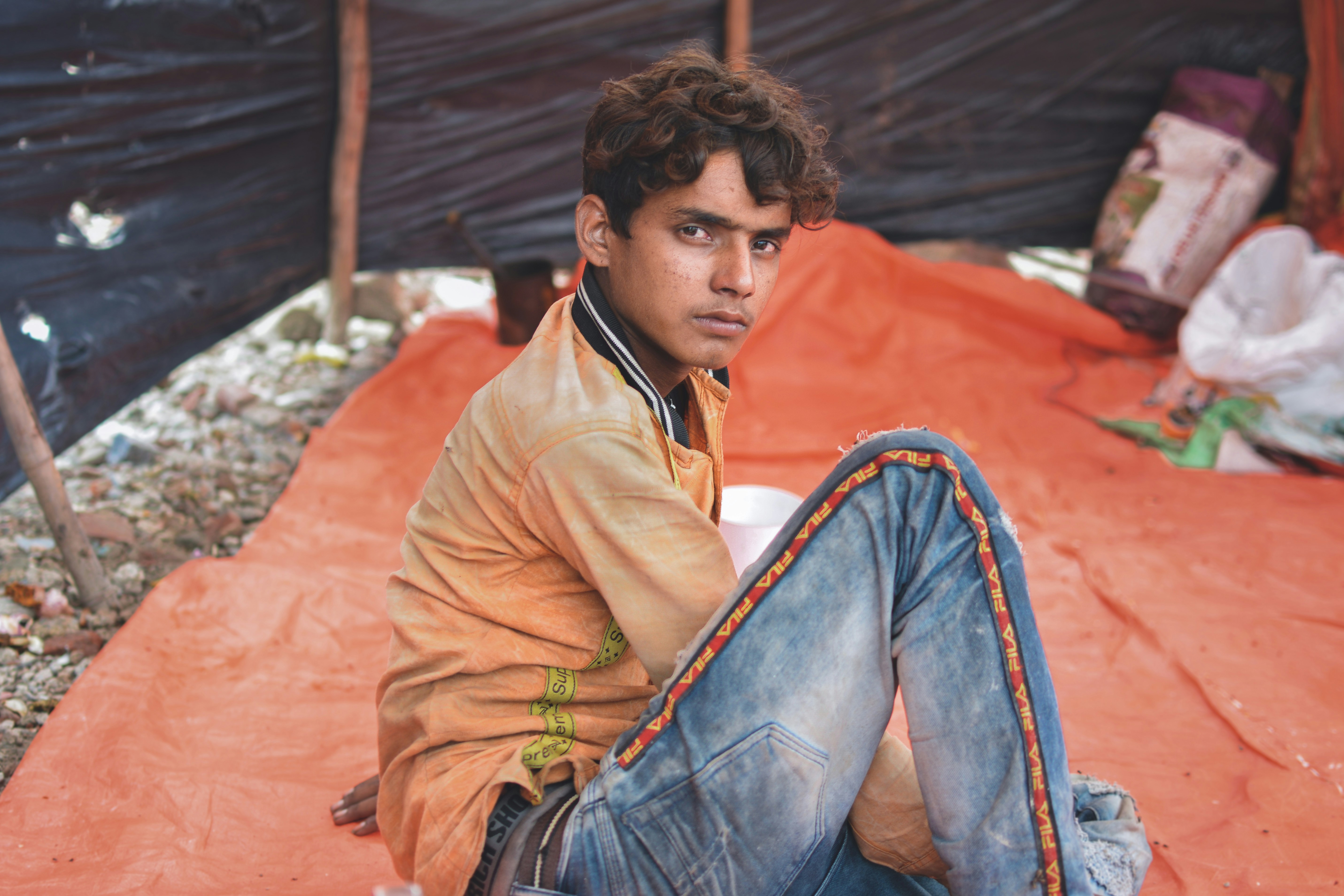 man wearing blue jeans sitting on orange textile