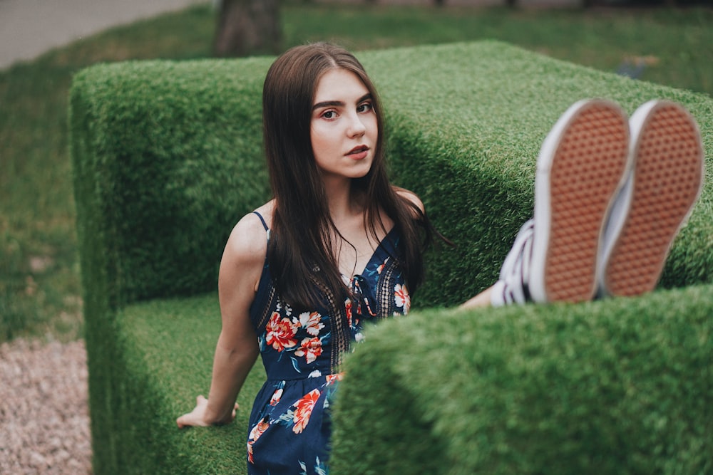 woman in black dress sitting on green grass bench