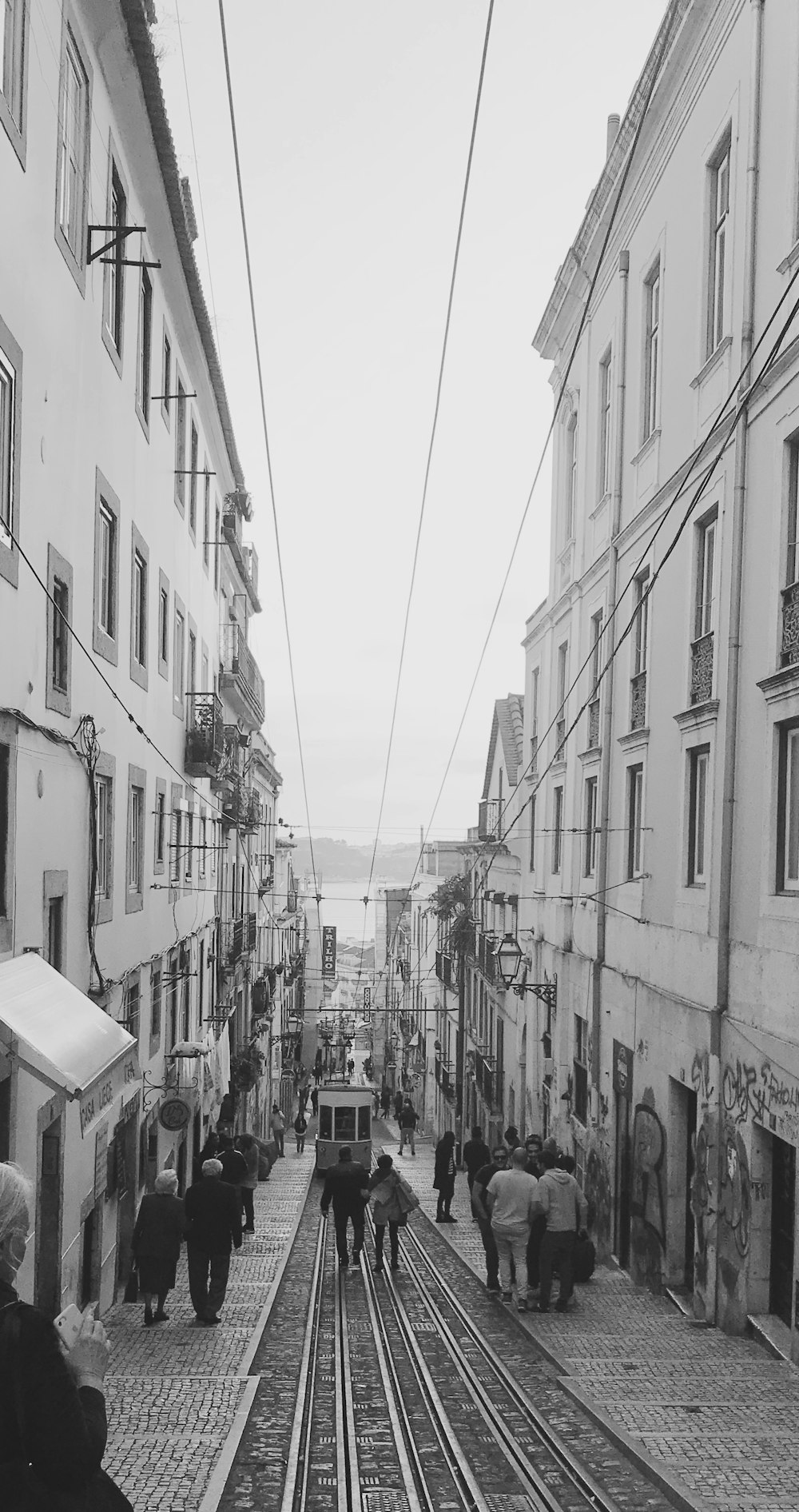 grayscale photo of people walking between buildings