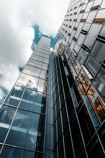 photographie en contre-plongée du bâtiment en verre d'une agence de marketing sous un ciel nuageux