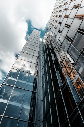 low angle photography of glass building under cloudy sky