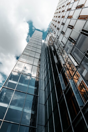 low angle photography of glass building under cloudy sky