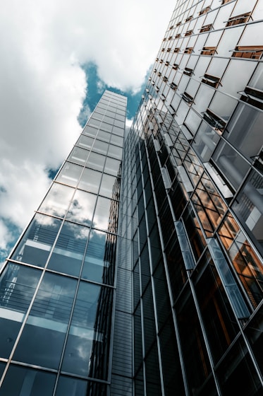 low angle photography of glass building under cloudy sky