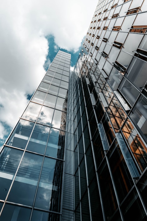 low angle photography of glass building under cloudy sky