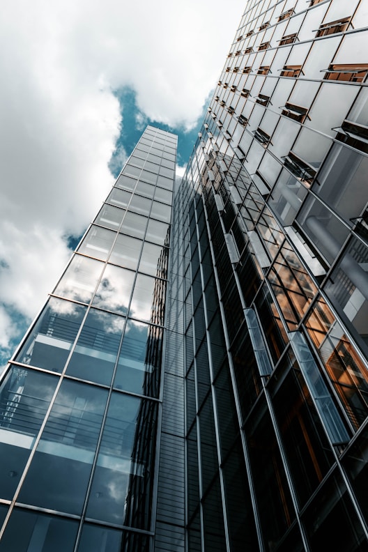 low angle photography of glass building under cloudy sky