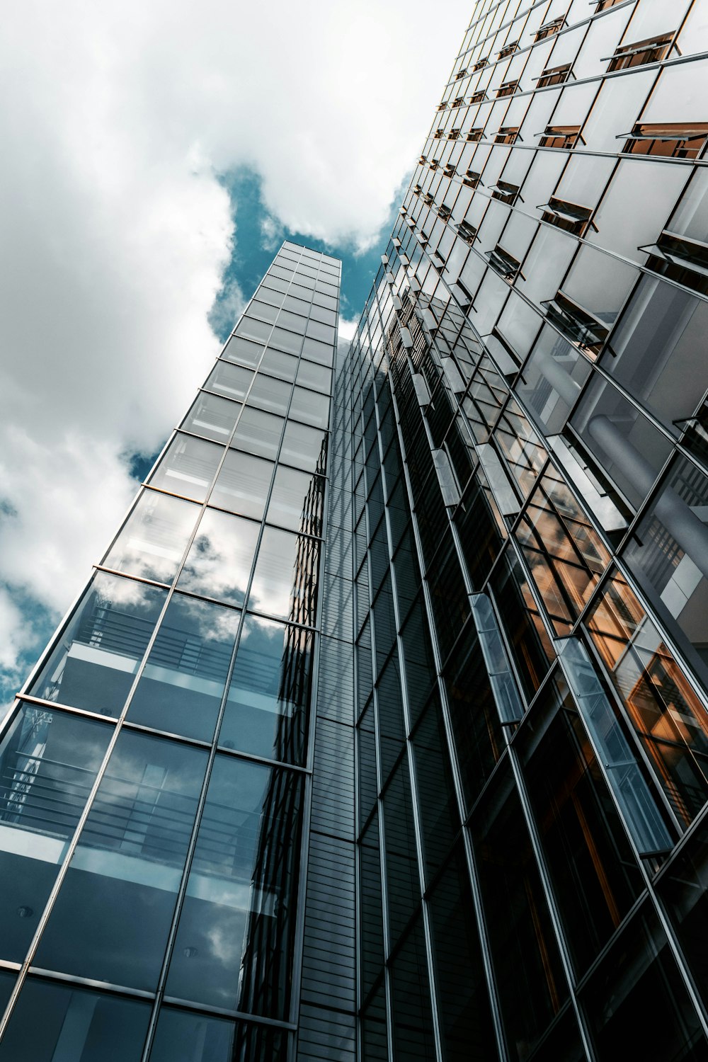 fotografia de baixo ângulo do edifício de vidro sob o céu nublado