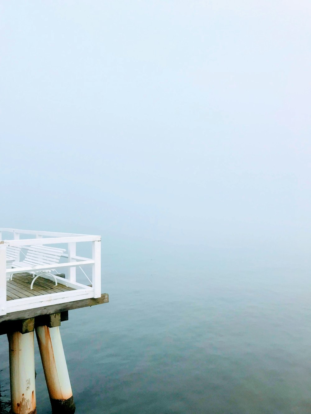 a white bench sitting on top of a wooden pier