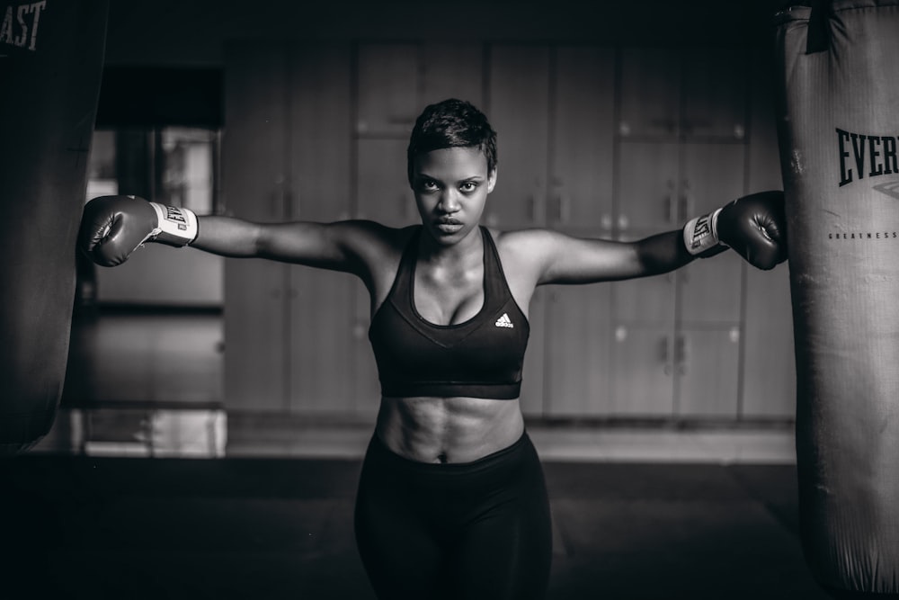 grayscale photo of woman with gloves touching heavy bags