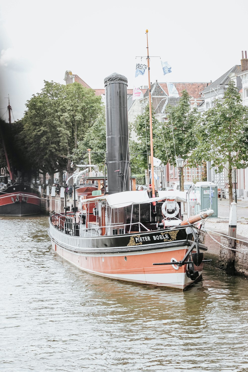 white and orange boat on calm body of water