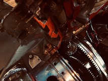 A close-up view of intricate mechanical gears and metal components, featuring detailed textures and reflections. The metal has a mixture of shiny and matte finishes, with visible bolts and labels.