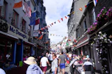A lively street scene showing local shops and smiling visitors enjoying the Boundary Road Festival.