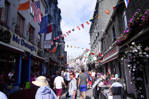 A lively street scene showing local shops and smiling visitors enjoying the Boundary Road Festival.