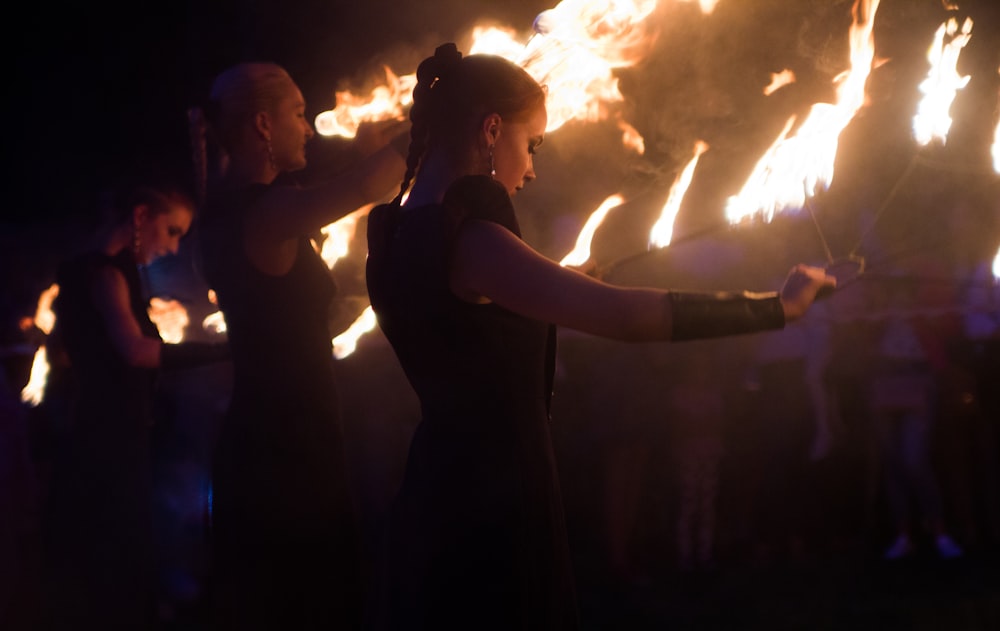 women standing and doing stunts using flames