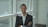 man wearing gray formal suit smiling while standing near glass window