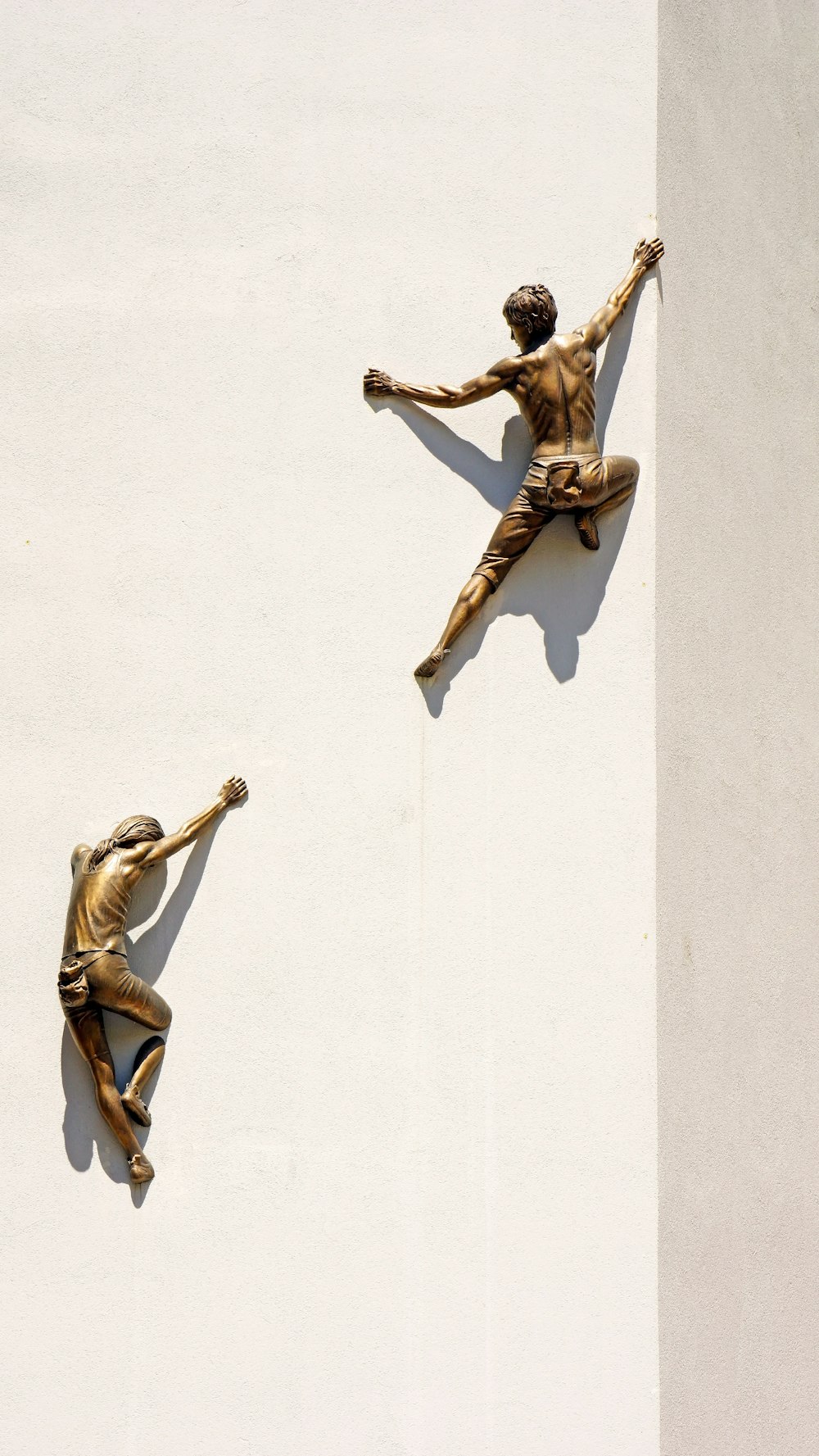brass statues of men climbing