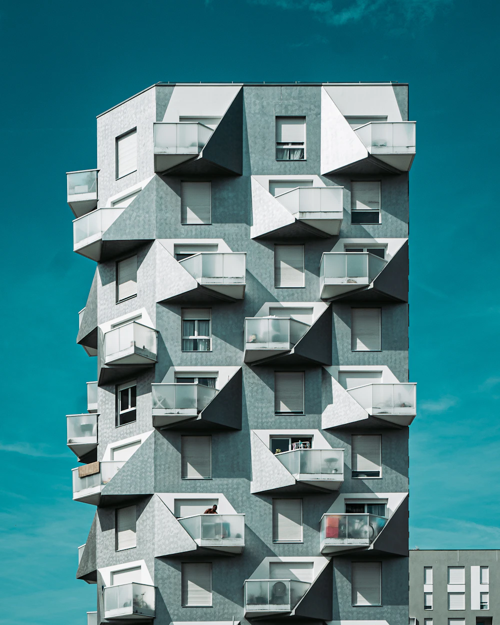 Tower with stacked, offset balconies against a clear sky